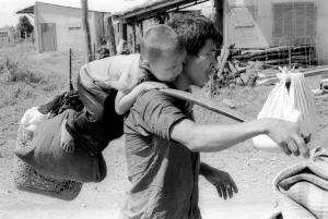 A South Vietnamese father carries his son and a bag of household possessions as he leaves his village near Trang Bom on Route 1 northwest of Saigon April 23, 1975. The area was becoming politically and militarily unstable as communist forces advanced, just days before the fall of Saigon.  (AP Photo/KY Mhan)
